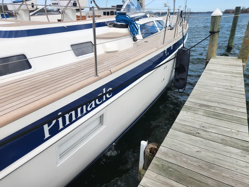 Slide: The Image of 2023 Hallberg-Rassy 57 yacht docked, featuring sleek design and wooden deck. - 5