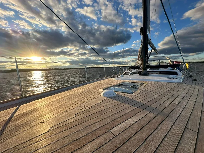 Slide: The Image of 2023 Hallberg-Rassy 57 yacht deck at sunset, sailing on calm waters. - 9
