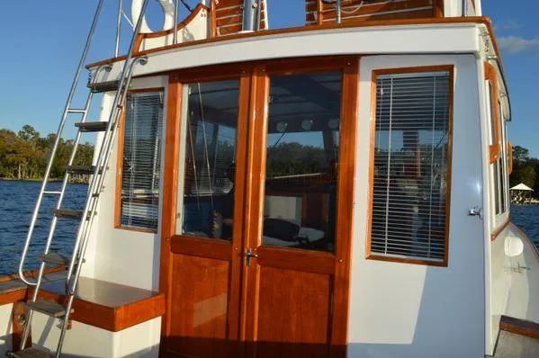 Slide: The Image of 1990 Stanley 36' Downeast Fly Bridge Cruise with wooden doors and windows, docked by water. - 14