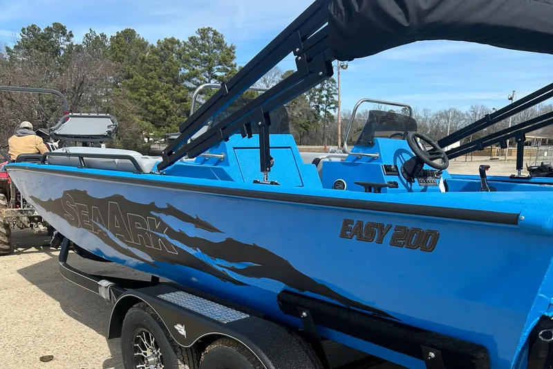 Slide: The Image of 2026 SeaArk Easy 200 boat on trailer by rocky shoreline. - 3