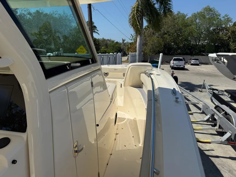 Slide: The Image of 2025 Scout 305 LXF boat, side view, parked outdoors under clear sky. - 13