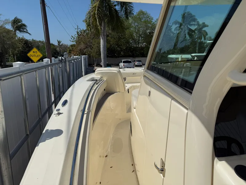 Slide: The Image of 2025 Scout 305 LXF boat, side view, parked near palm trees and a "No Outlet" sign. - 14