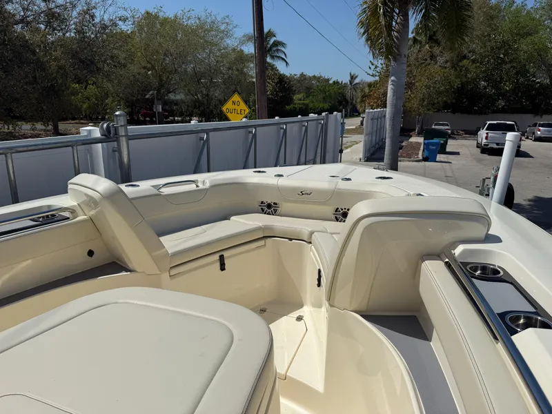 Slide: The Image of 2025 Scout 305 LXF boat interior with seating and cup holders, parked outdoors. - 16