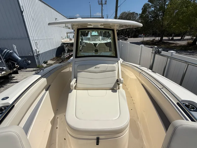 Slide: The Image of 2025 Scout 305 LXF boat interior with seating and console, docked outdoors. - 18