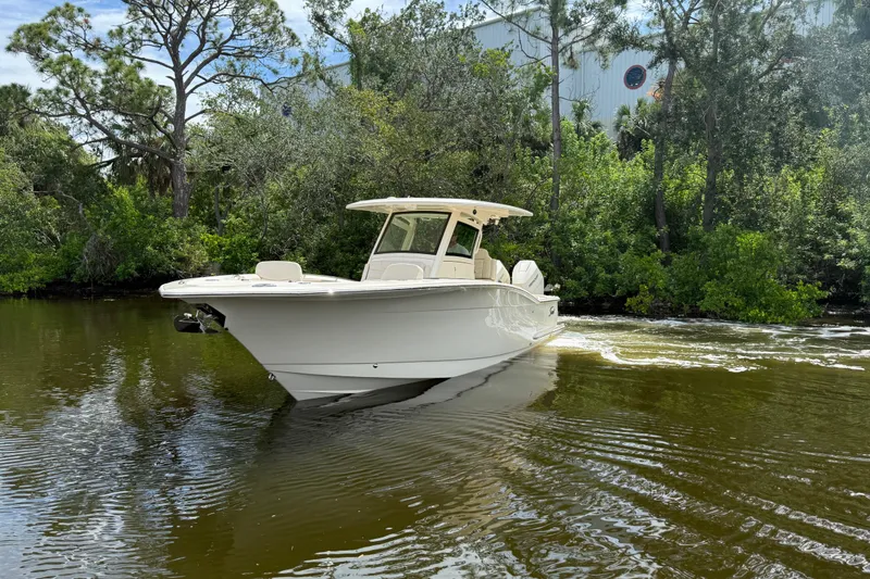 Slide: The Image of 2025 Scout 305 LXF boat cruising on a calm river surrounded by lush greenery. - 2