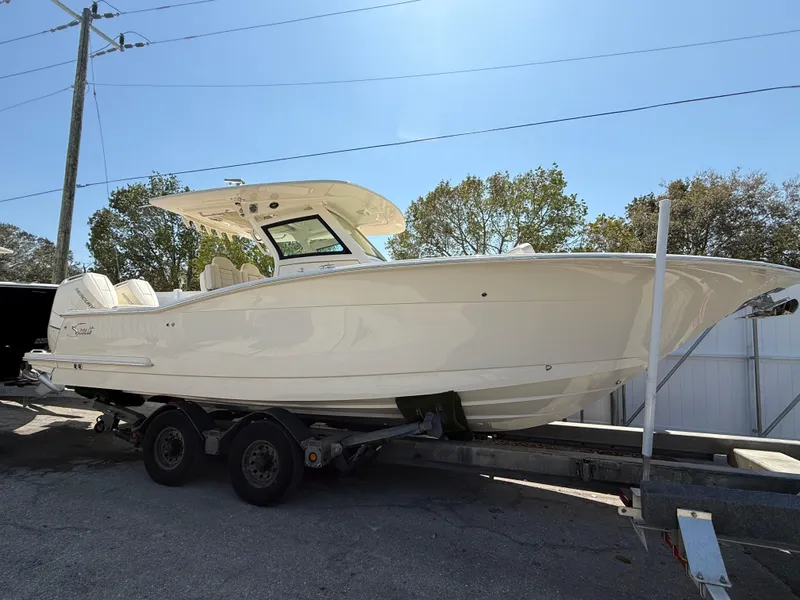 Slide: The Image of 2025 Scout 305 LXF boat on trailer, parked outdoors under clear sky. - 4