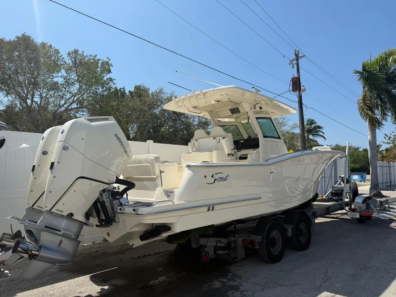 Slide: The Image of 2025 Scout 305 LXF boat on trailer, parked outdoors under clear sky. - 5