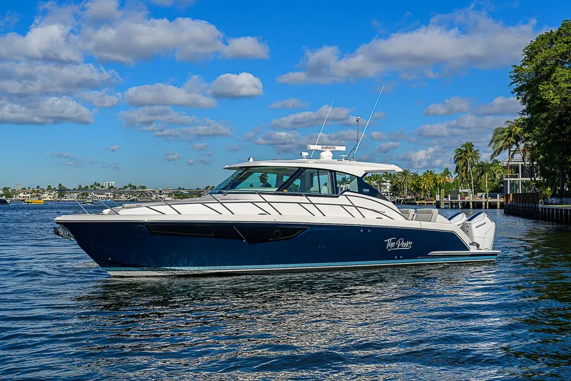 Slide: The Image of 2023 Tiara Yachts 43 LE cruising on a sunny day, surrounded by calm waters and lush greenery. - 4
