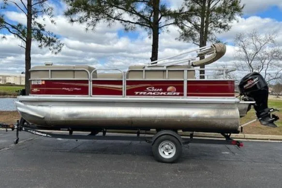 Slide: The Image of 2023 Sun Tracker Party Barge 18 DLX pontoon boat on trailer, parked outdoors. - 2