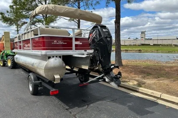 Slide: The Image of 2023 Sun Tracker Party Barge 18 DLX pontoon boat on trailer near a lake. - 5