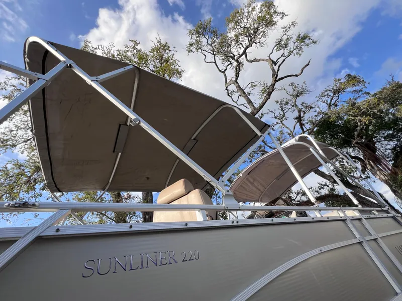 Slide: The Image of 2013 Harris FloteBote Sunliner 220 pontoon boat with canopy, under a blue sky. - 25