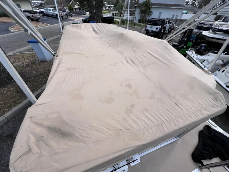 Slide: The Image of 2013 Harris FloteBote Sunliner 220 with beige cover in a marina setting. - 30