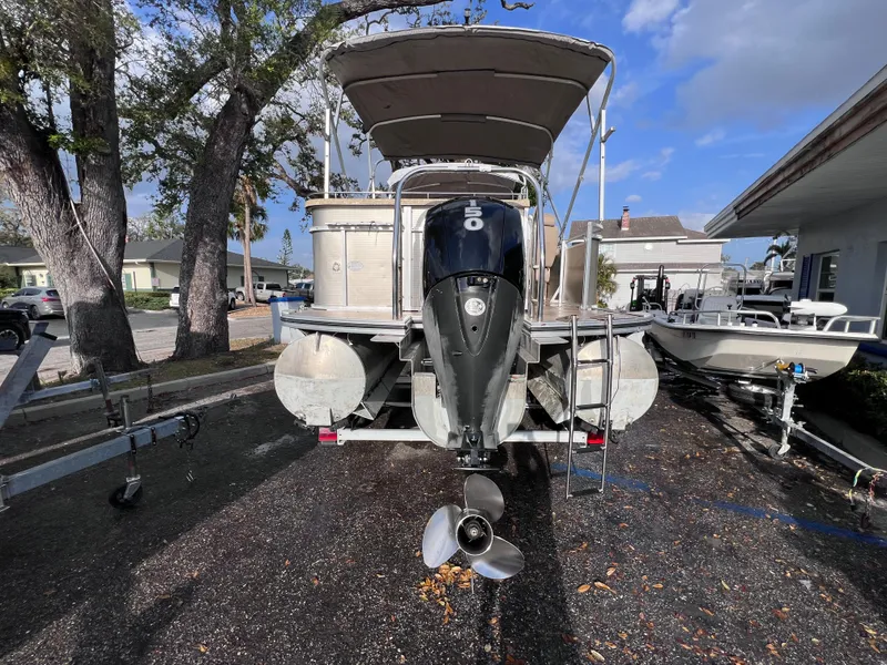 Slide: The Image of 2013 Harris FloteBote Sunliner 220 pontoon boat with outboard motor, parked on a trailer. - 5