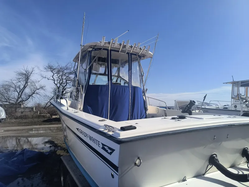 Slide: The Image of 1988 Grady-White 255 Sailfish Walkaround boat with blue canopy, docked under clear sky. - 4