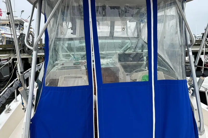 Slide: The Image of 1988 Grady-White 255 Sailfish Walkaround with blue canvas enclosure at dock. - 5