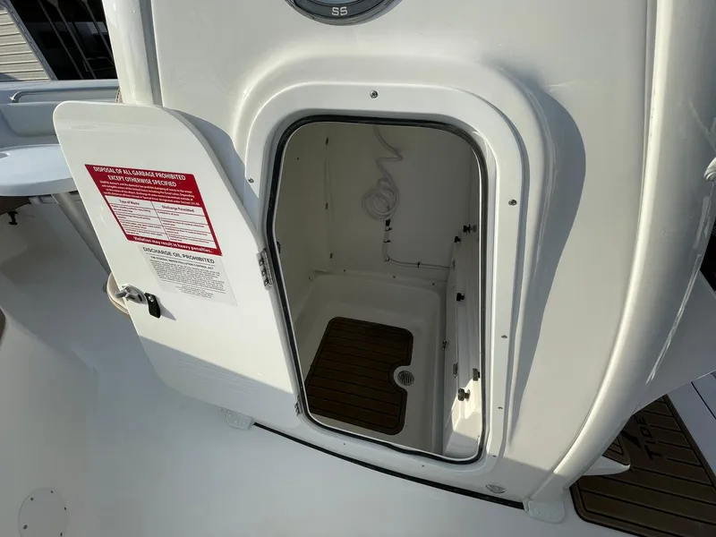 Slide: The Image of 2025 Tidewater 232 SS boat storage compartment with open door, showcasing interior space. - 18