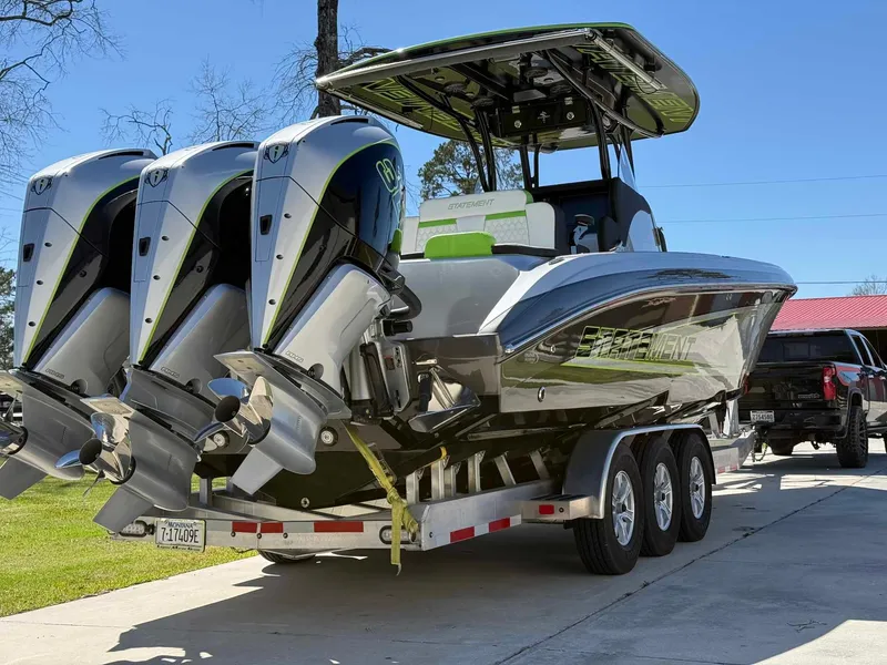 Slide: The Image of 2024 Statement 350 Open boat on trailer with triple engines, parked outdoors. - 2