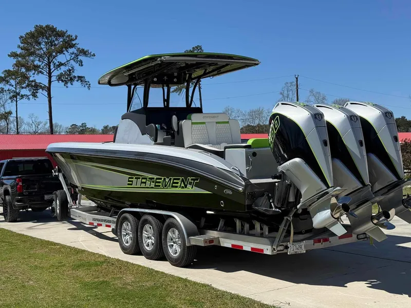 Slide: The Image of 2024 Statement 350 Open boat on trailer with triple engines, parked outdoors. - 4