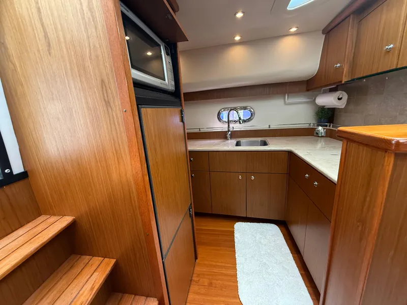Slide: The Image of 2014 Tiara Yachts 4500 Sovran kitchen with wood cabinetry, sink, and microwave. - 48