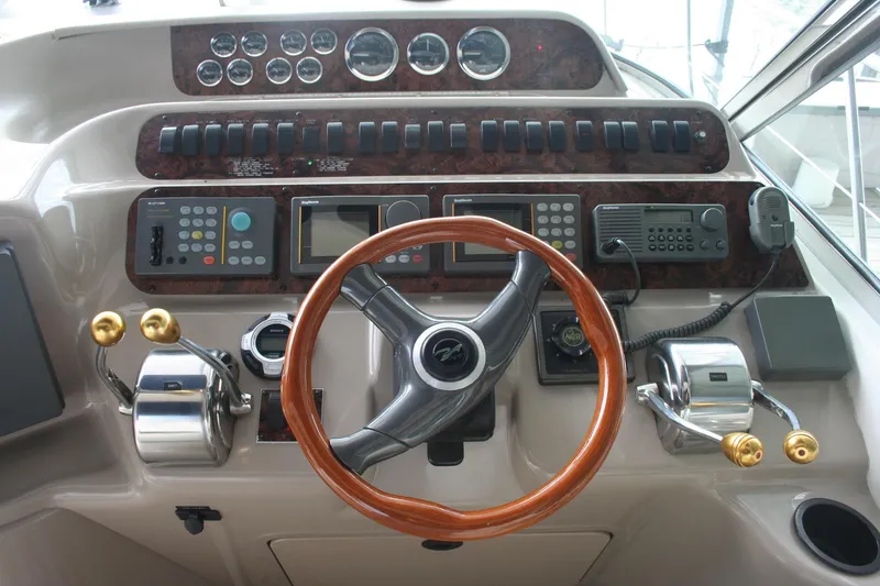 Slide: The Image of 1999 Sea Ray 400 Sundancer helm with wood steering wheel and control panels. - 28