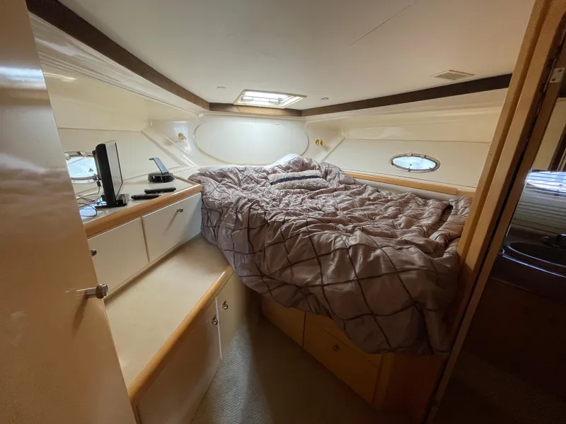 Slide: The Image of Interior of 2000 Carver 350 Mariner with bed, fan, and TV on a wooden shelf. - 26