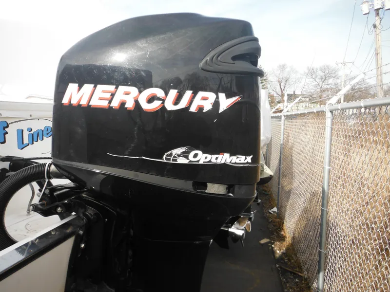 Slide: The Image of Mercury Optimax outboard motor on 1999 Robalo 2440 Walkaround boat, parked near chain-link fence. - 11