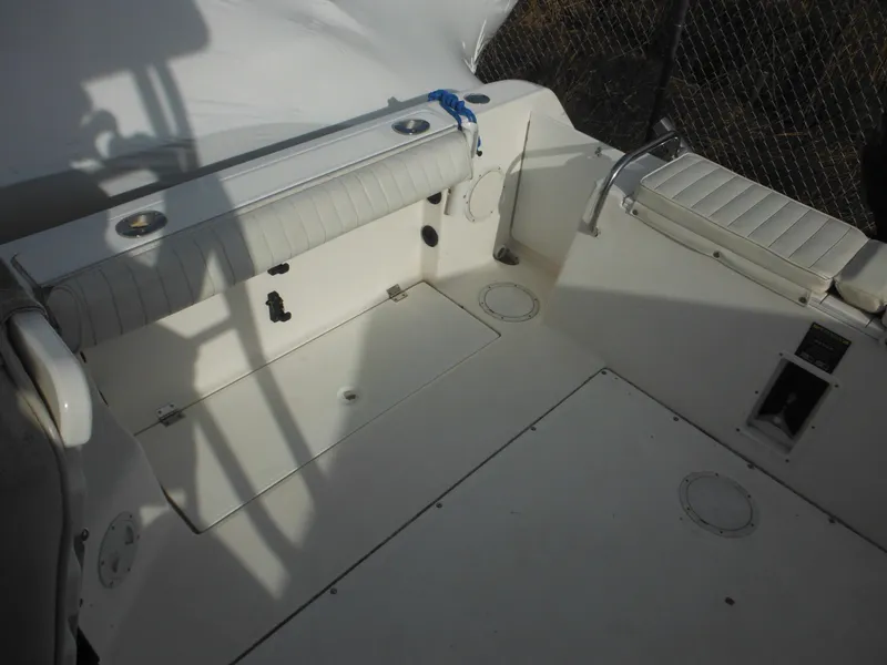 Slide: The Image of 1999 Robalo 2440 Walkaround boat interior with white seating and storage compartments. - 15