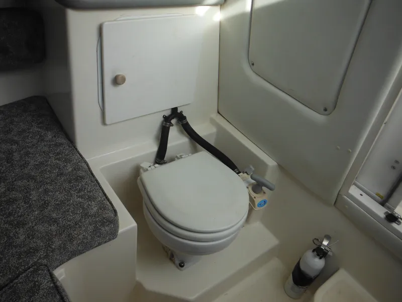 Slide: The Image of 1999 Robalo 2440 Walkaround boat interior with compact marine toilet and storage cabinet. - 28