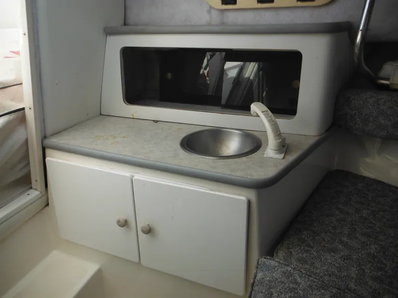 Slide: The Image of 1999 Robalo 2440 Walkaround boat interior with sink and storage cabinets. - 29