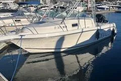 Slide: The Image of 1999 Robalo 2440 Walkaround boat docked in a marina, reflecting on the water. - 3
