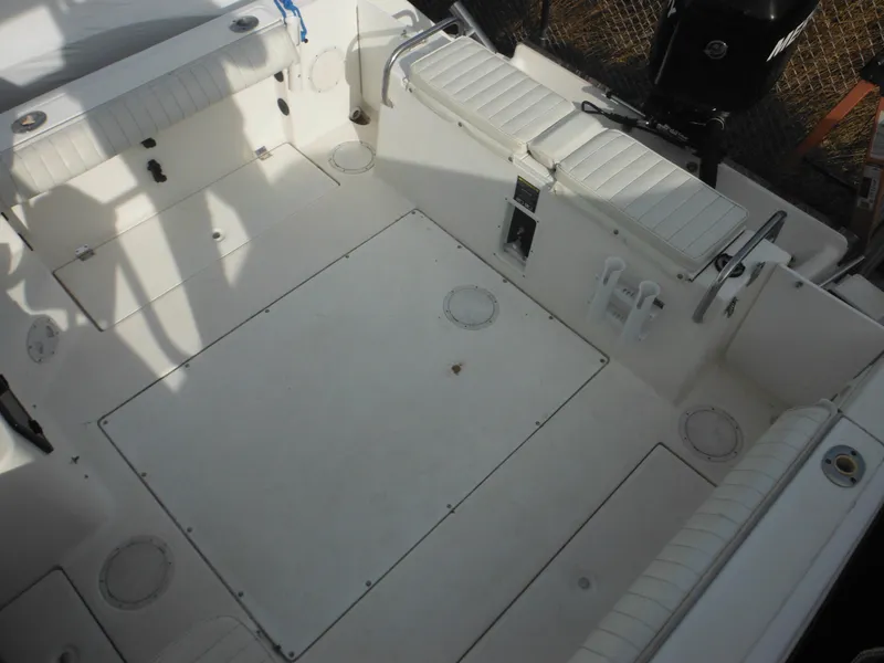 Slide: The Image of 1999 Robalo 2440 Walkaround boat interior with white seating and storage compartments. - 43