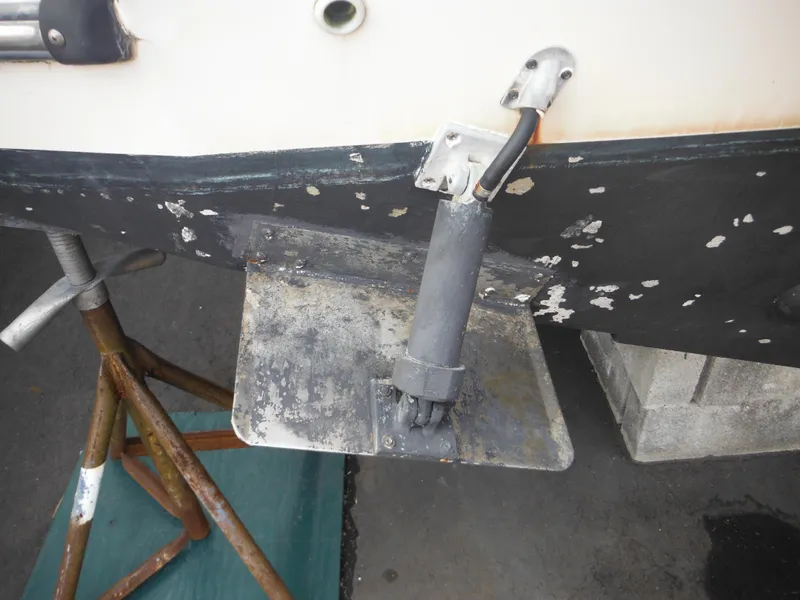 Slide: The Image of 1999 Robalo 2440 Walkaround boat trim tab with hydraulic actuator, showing wear and corrosion. - 47