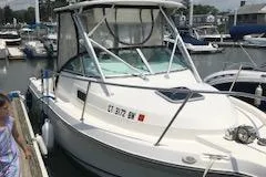 Slide: The Image of 1999 Robalo 2440 Walkaround boat docked at a marina, featuring a white exterior. - 6