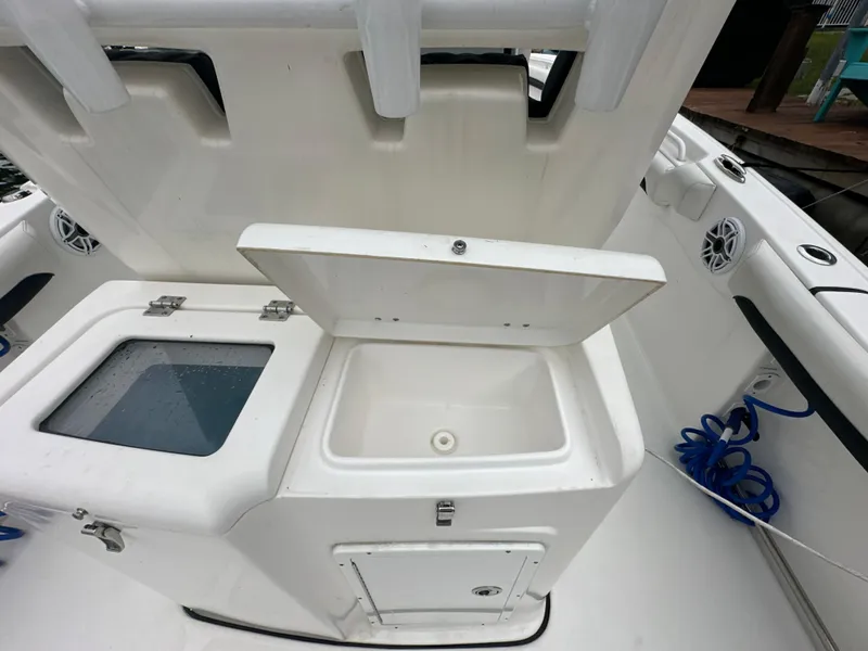 Slide: The Image of 2022 Tidewater 280 CC Adventure boat with open storage compartment and seating area. - 13