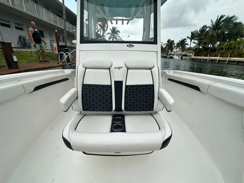 Slide: The Image of 2022 Tidewater 280 CC Adventure boat with cushioned seating, dockside view, and palm trees in the background. - 21