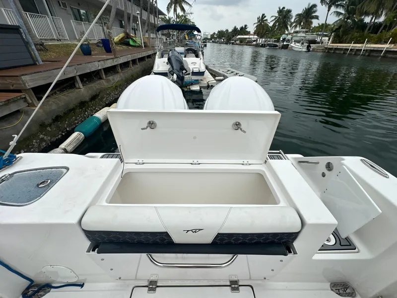 Slide: The Image of 2022 Tidewater 280 CC Adventure boat with open storage compartment, docked by a canal. - 6