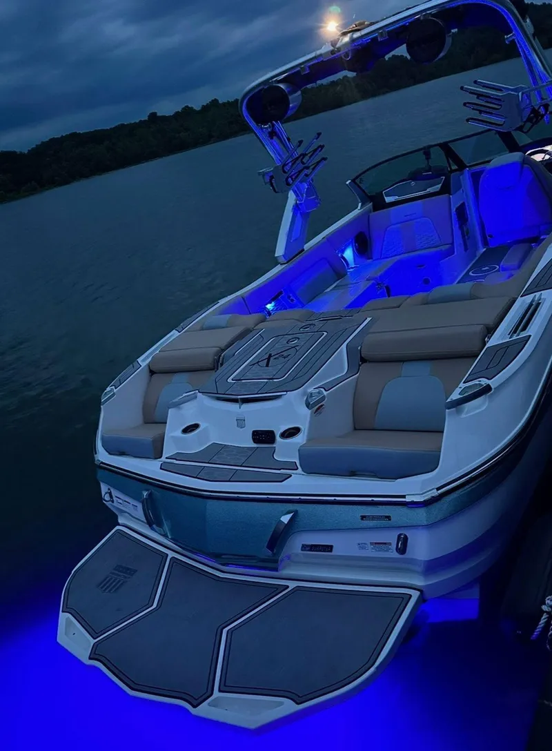 Slide: The Image of 2023 MasterCraft X24 boat with blue LED lights on a lake at dusk. - 15