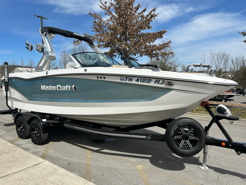 Slide: The Image of 2023 MasterCraft X24 boat on trailer, parked outdoors under clear sky. - 3