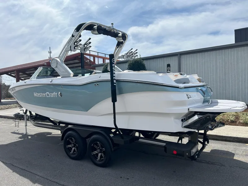 Slide: The Image of 2023 MasterCraft X24 boat on trailer, parked outdoors, side view. - 4