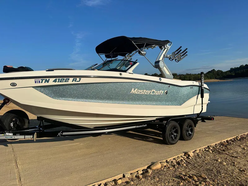 Slide: The Image of 2023 MasterCraft X24 boat on trailer by a lake, ready for launch. - 6