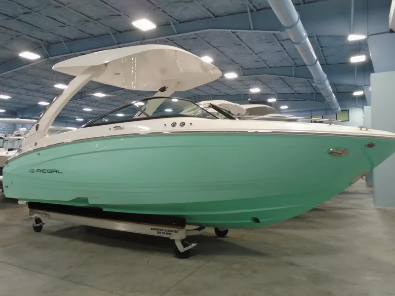 The Image of 2025 Regal LX4 boat in showroom, featuring sleek turquoise hull and modern design. - 1