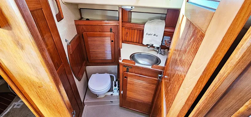 Slide: The Image of 1988 Island Packet 38 yacht bathroom with wooden cabinetry, sink, and toilet. - 10