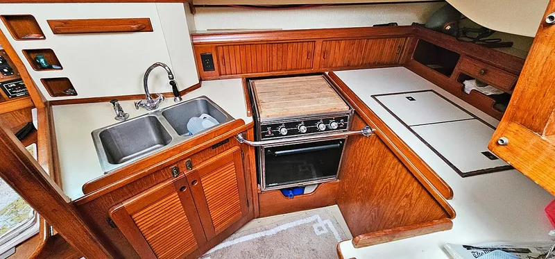 Slide: The Image of 1988 Island Packet 38 yacht kitchen with wooden cabinetry, dual sink, and stove. - 6