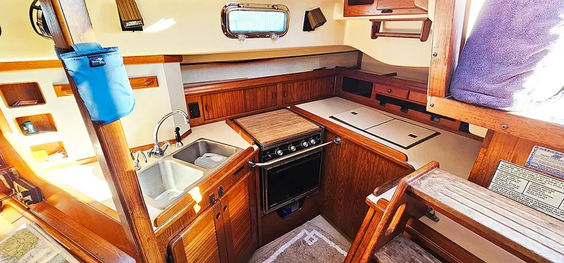 Slide: The Image of 1988 Island Packet 38 sailboat kitchen with wood cabinetry and stainless steel sink. - 9