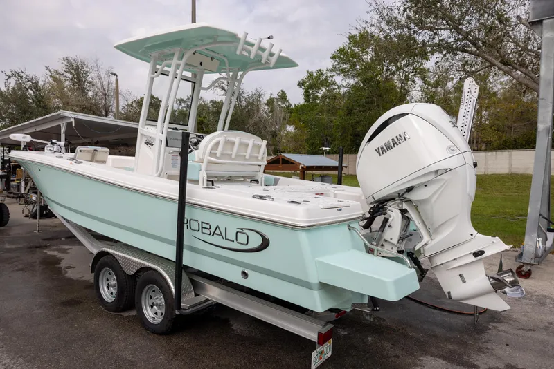 Slide: The Image of 2023 Robalo 246 Cayman boat with Yamaha engine on trailer, parked outdoors. - 2