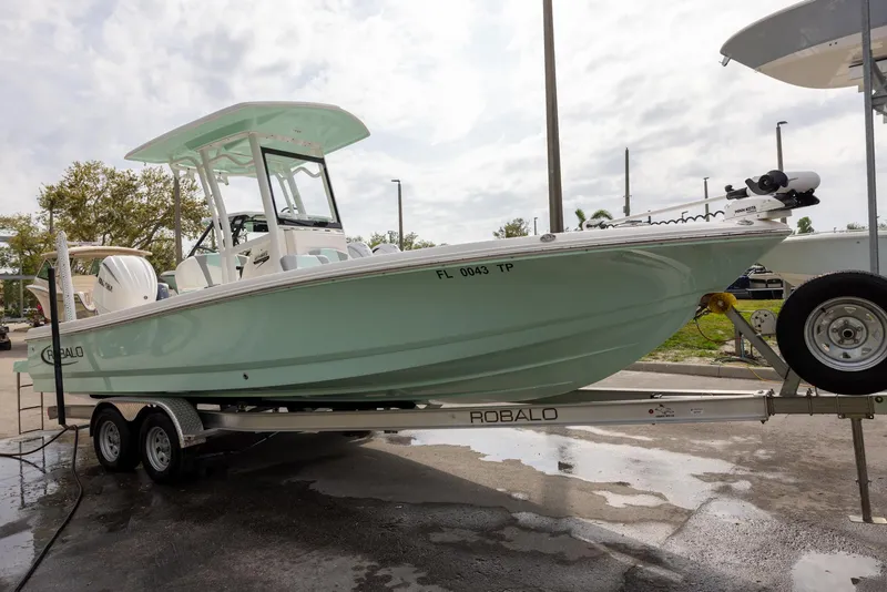 Slide: The Image of 2023 Robalo 246 Cayman boat on trailer, light green hull, parked outdoors. - 6