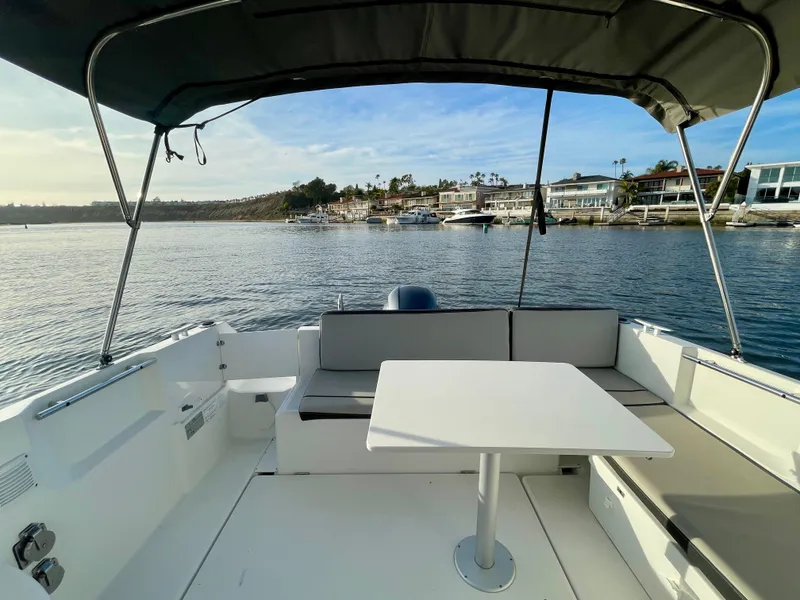 Slide: The Image of 2020 Jeanneau NC 795 boat interior with seating and table, overlooking a scenic waterfront. - 23