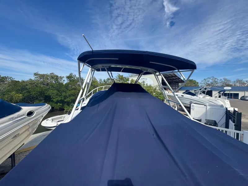 Slide: The Image of 1996 Intrepid 356 Cuddy boat covered with a blue tarp, docked outdoors. - 4