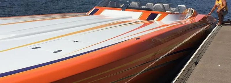 Slide: The Image of 2014 Nordic Powerboats 43 Enforcer with vibrant orange and white design docked by the water. - 3