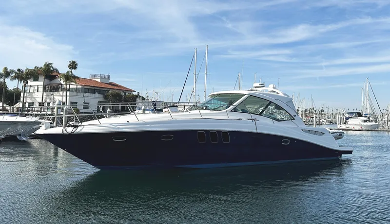 Slide: The Image of 2006 Sea Ray 48 Sundancer yacht docked in a marina under a clear blue sky. - 2